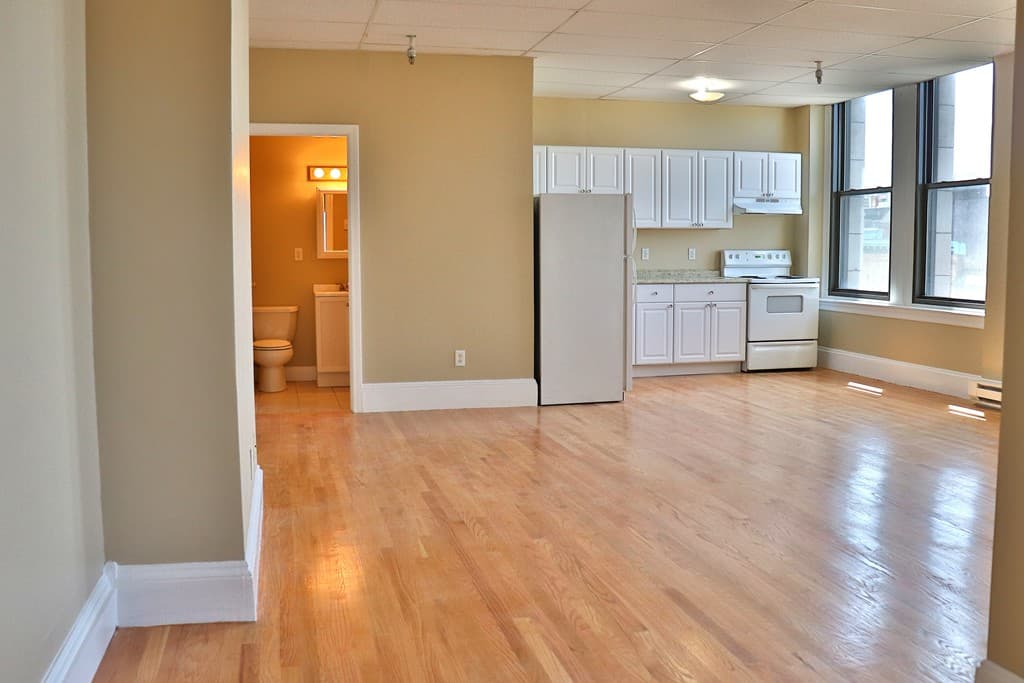 Open kitchen and living layout with white cabinets and refinished hardwood floors at 111 Lawrence Street #606