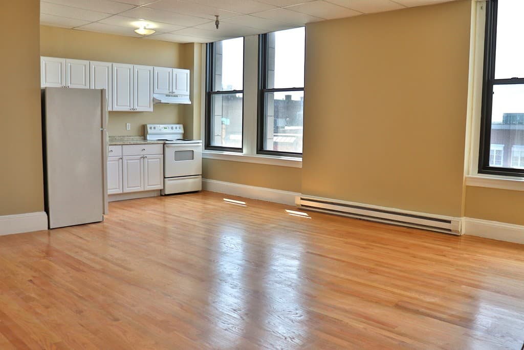 Living and kitchen area with abundant natural light and tall windows at 111 Lawrence Street #606