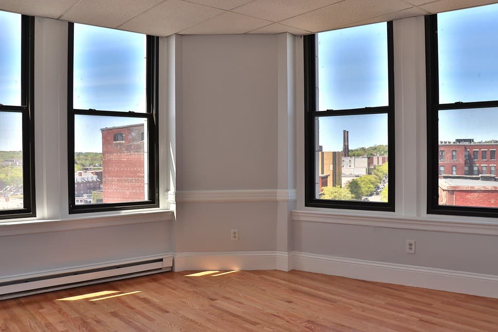 Sunlit corner living room with bay windows and downtown Lawrence skyline view at 111 Lawrence Street